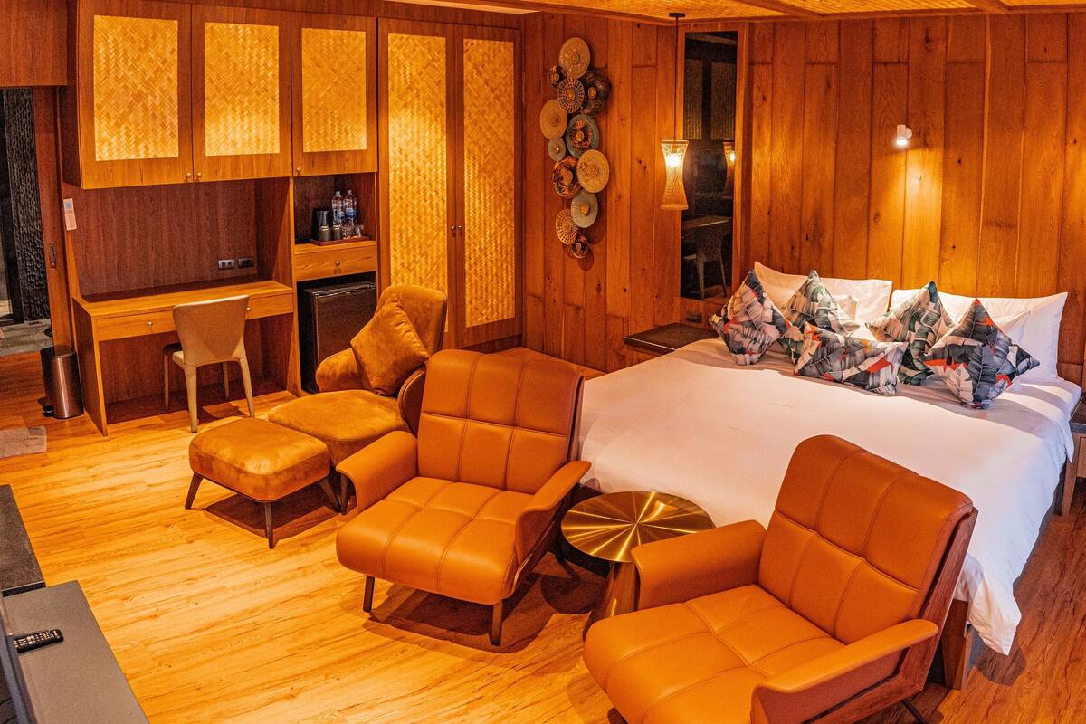 A hotel room with a large bed, two sofas, a desk, and a small table.