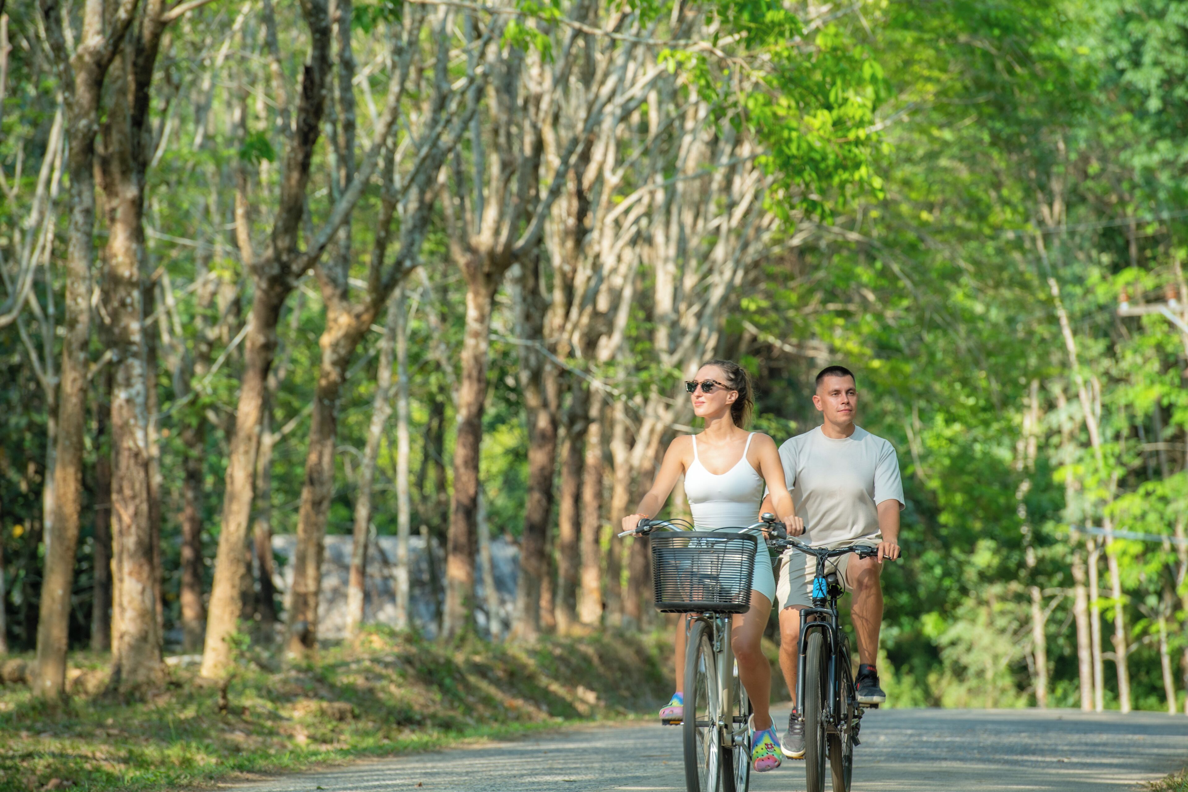 Dos personas andando en bicicleta por un sendero bordeado de árboles.