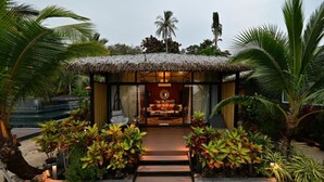 A thatched-roof structure with a bed and a small table, surrounded by tropical plants. - Big Sun Residence by iRETREAT (Ko Yao)