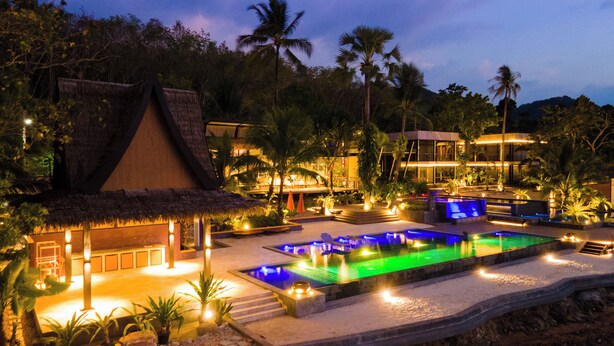 A resort with a swimming pool, thatched-roof structures, and lush greenery. - Big Sun Residence by iRETREAT (Ko Yao)