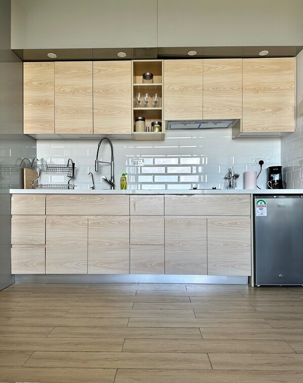 Una cocina moderna con armarios de madera, un refrigerador de acero inoxidable y un salpicadero de azulejos.