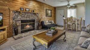 A living room with a stone fireplace, a sofa, a coffee table, and a dining area with a table and chairs.