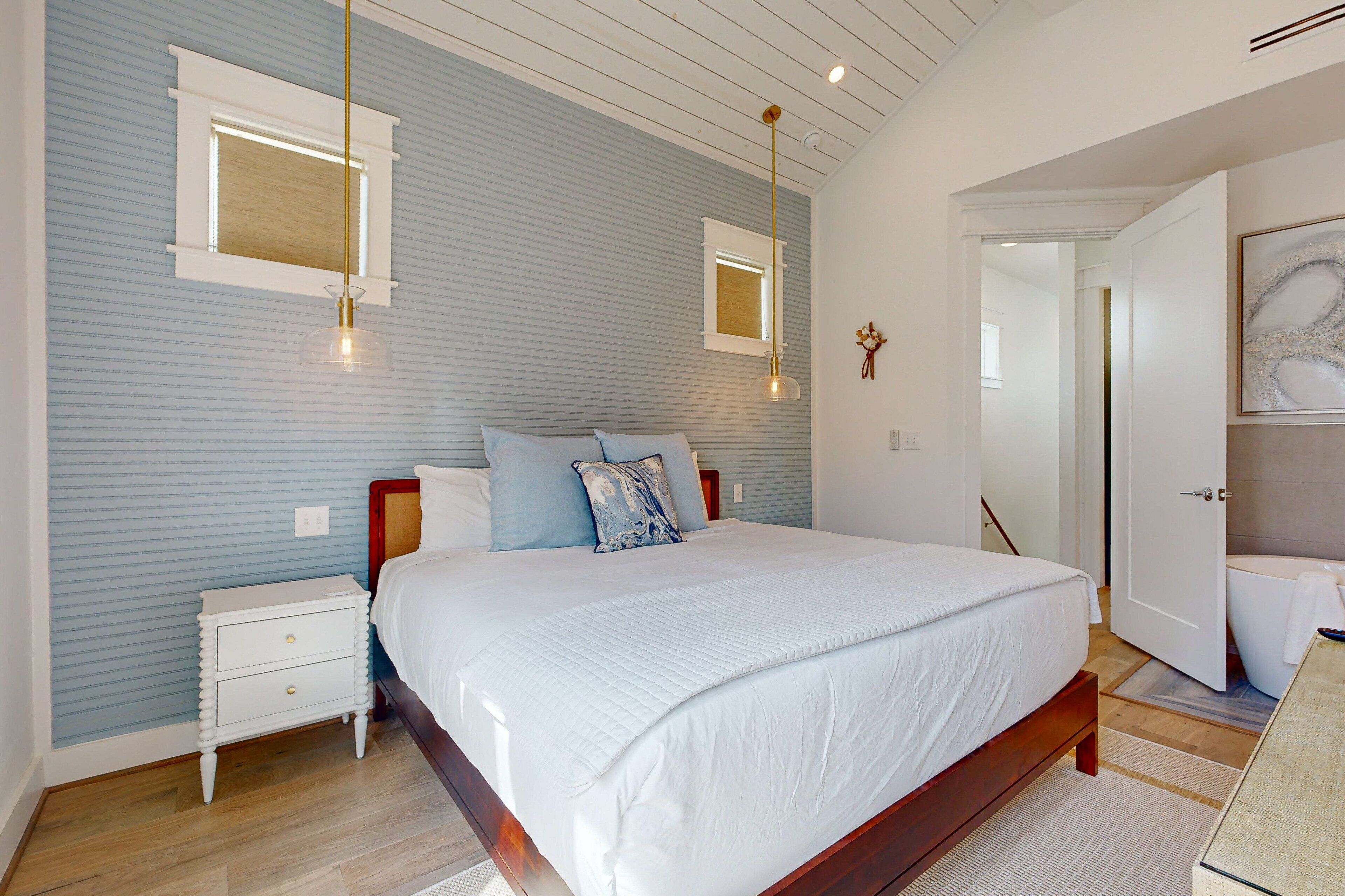 Un dormitorio con una cama grande, una mesita de noche, una ventana y una puerta que da al baño.