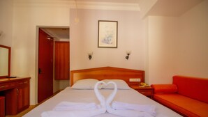 A hotel room with a bed, a red sofa, a wooden nightstand, and a framed picture on the wall. - Celeste Hotel (Fethiye)