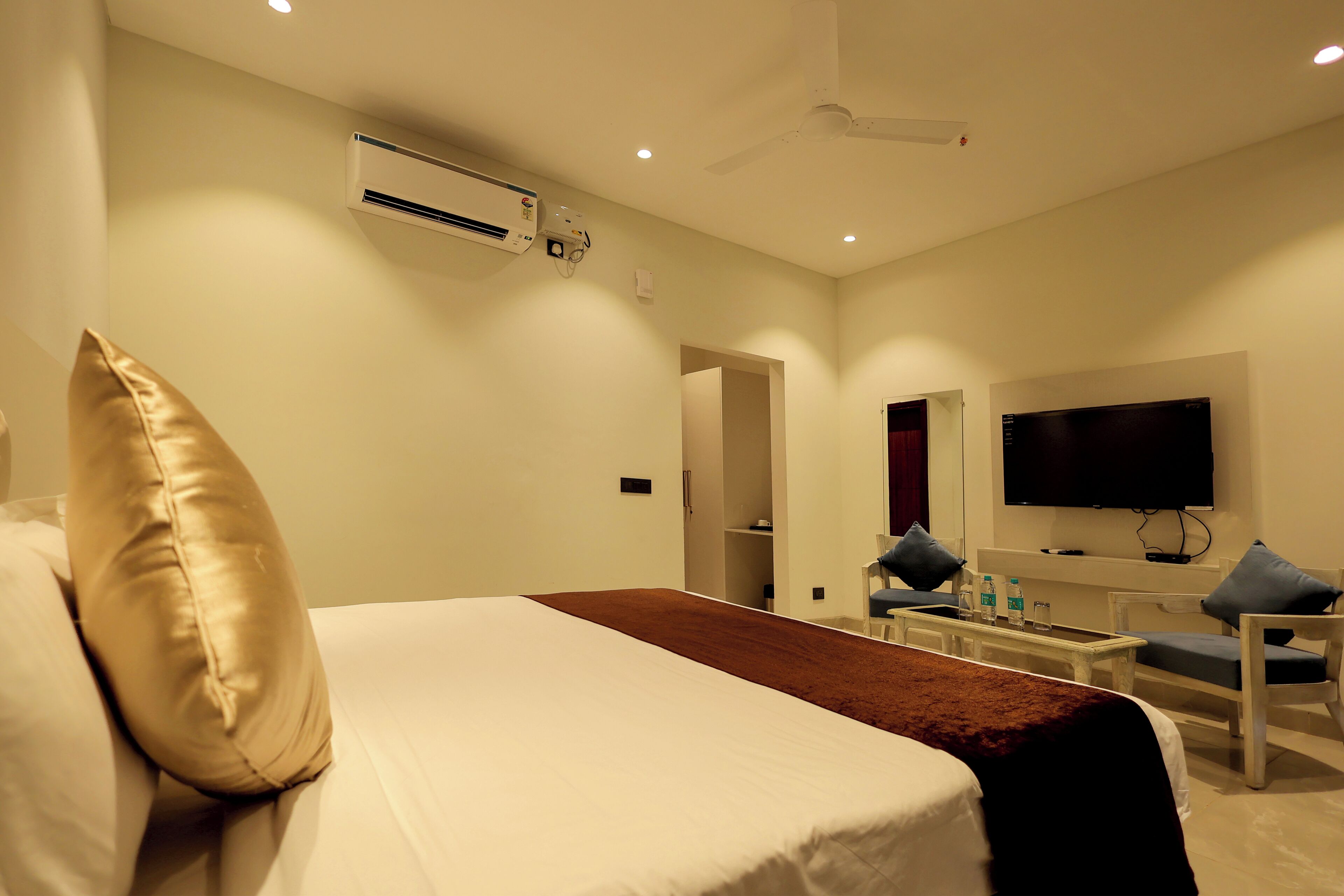 Una habitación de hotel con una cama, televisión, escritorio y una silla.