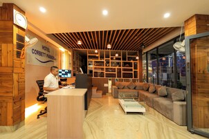 A hotel reception area with a wooden reception desk, a sofa, and a glass coffee table.