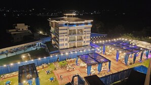 A multi-story hotel with a rooftop terrace, outdoor seating, and a stage for events. - Hotel Corbett Paradise Kotdwar (Lansdowne)