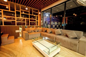 A modern living room with a sectional sofa, a glass coffee table, and a wooden accent wall with shelves.