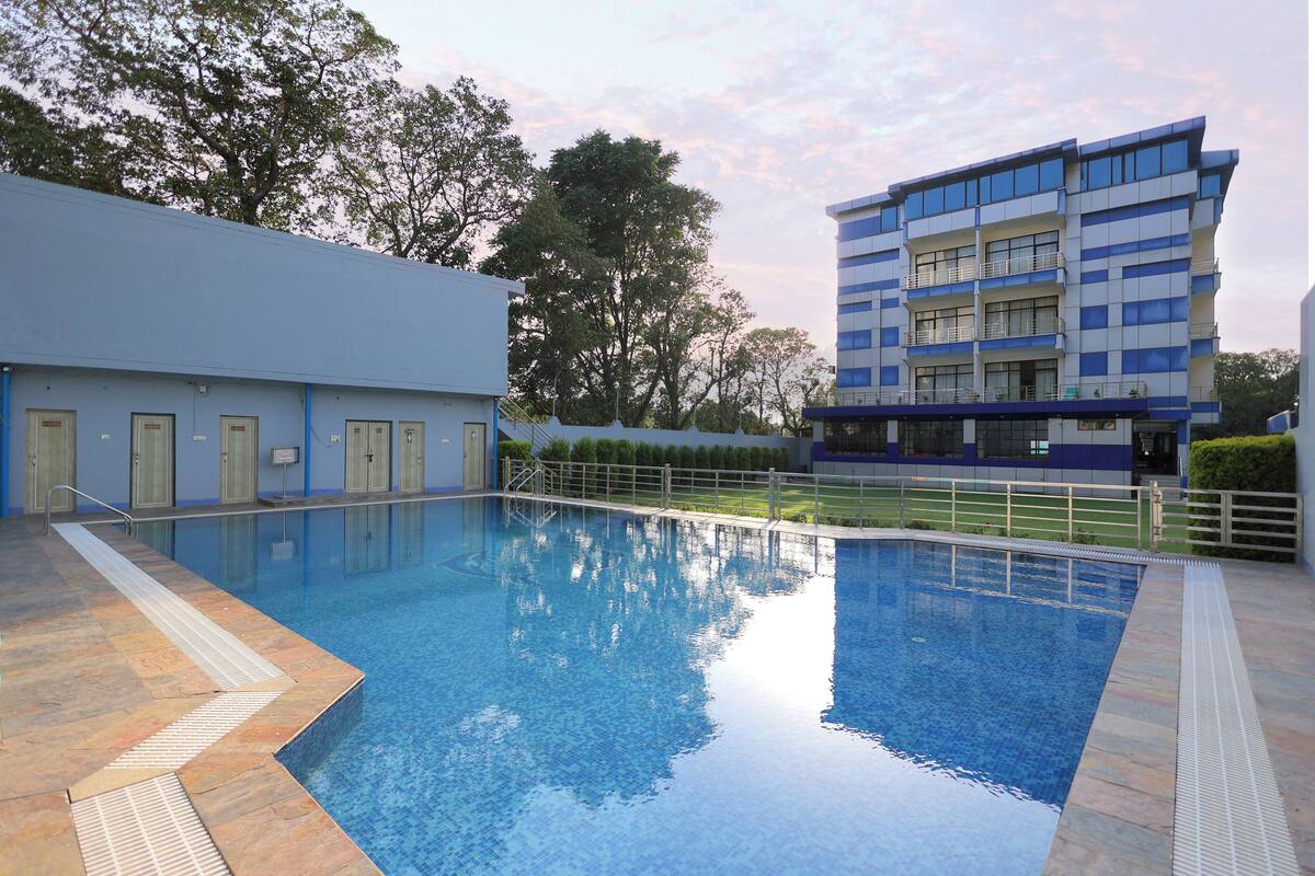 A swimming pool with a clear blue water surface, surrounded by a tiled deck and a low fence.