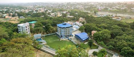 Un barrio residencial con un edificio de techo azul destacado, rodeado de vegetación y otras viviendas.