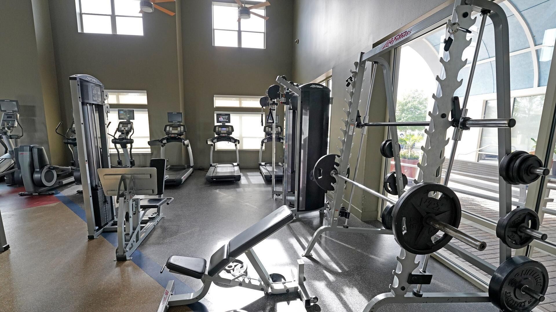 Een fitnessruimte met loopbanden, krachtapparaten en losse gewichten.