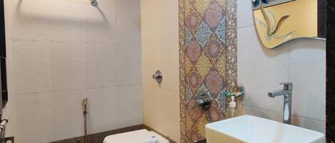 Baño con inodoro, lavabo, ducha y toallero.