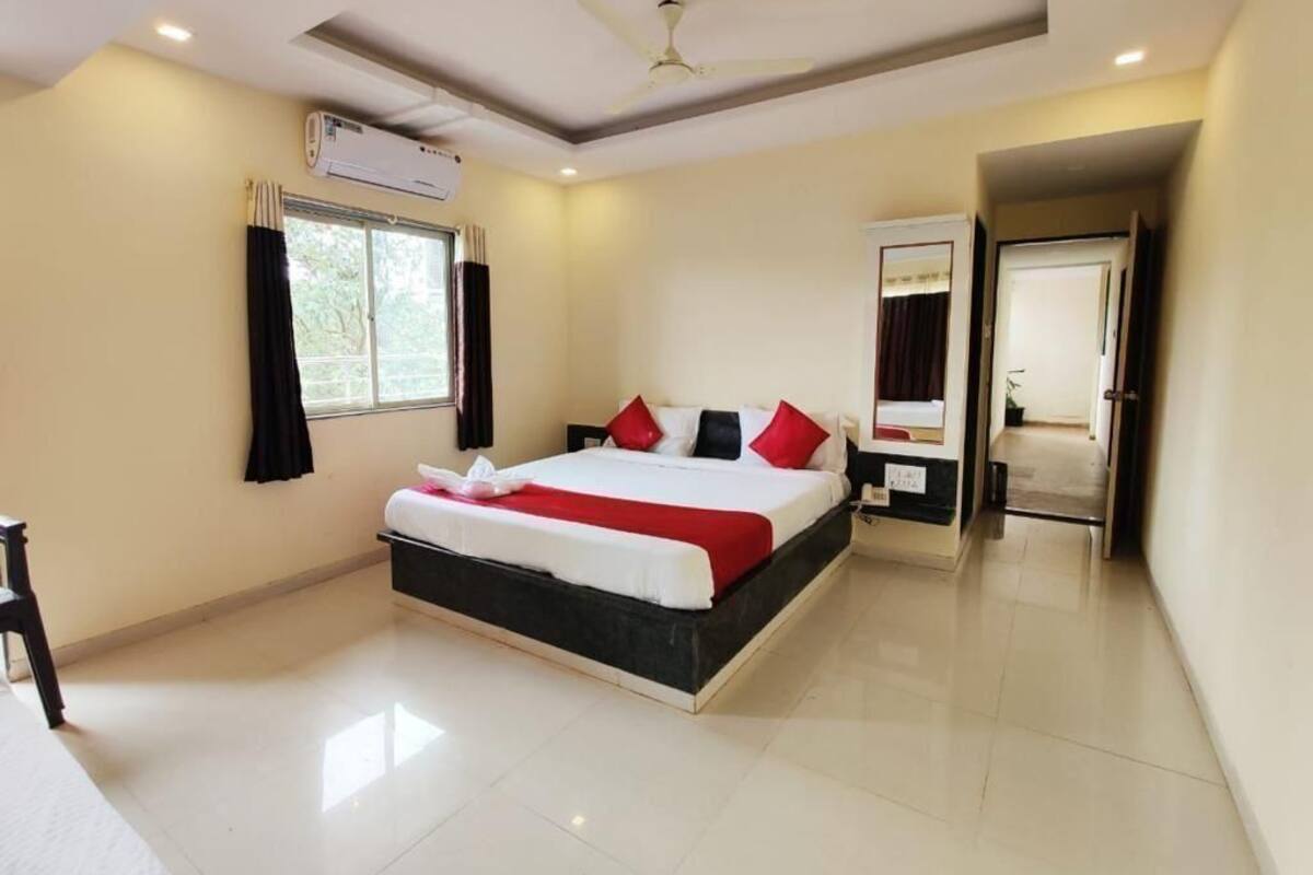 A bedroom with a bed, a ceiling fan, an air conditioning unit, and a window with curtains.