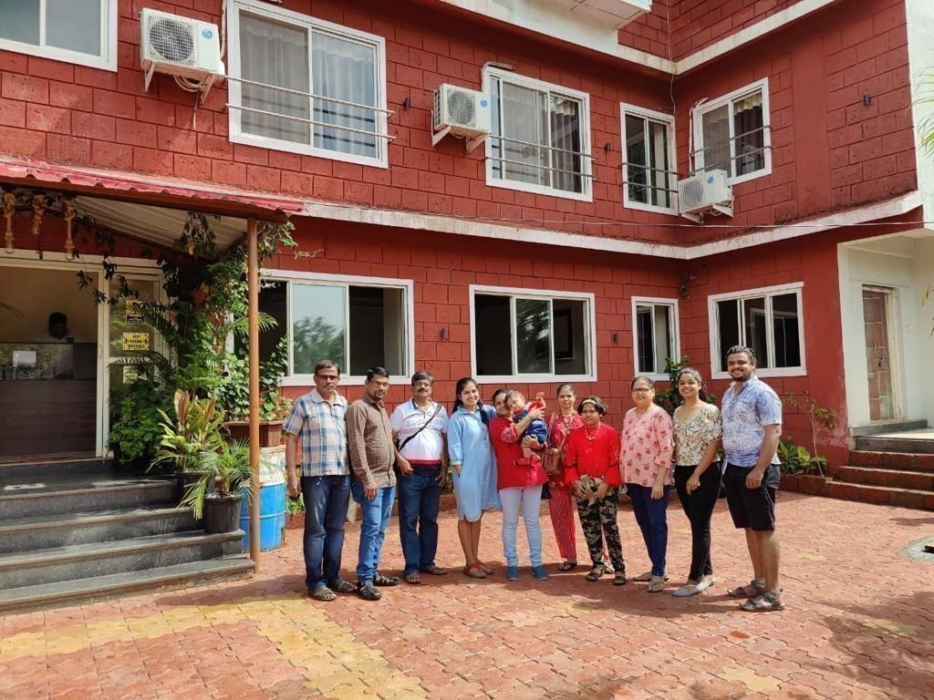 A group of people standing in front of a red brick building with multiple windows and air conditioning units.