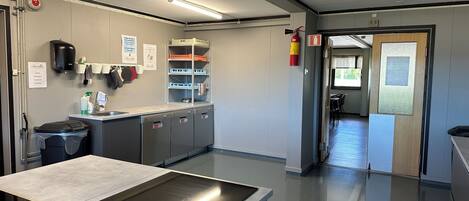 A modern kitchen with stainless steel appliances, a sink, and a countertop with a built-in induction cooktop. There are storage cabinets and a fire extinguisher visible.