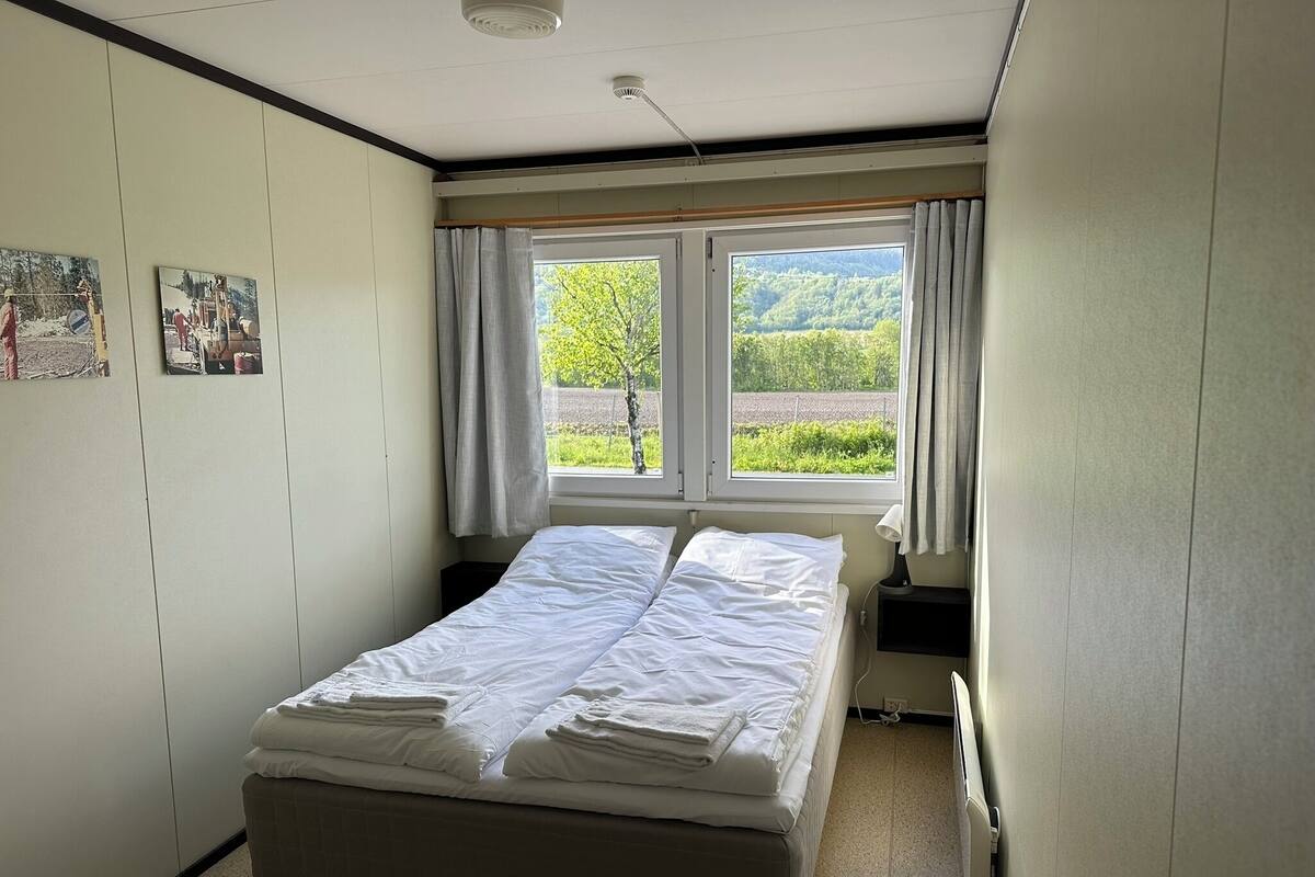 Un dormitorio con cama, ventana con cortinas y radiador.