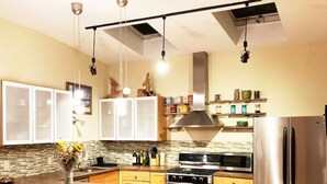 A modern kitchen with a central island, stainless steel appliances, wooden cabinets, and a patterned rug. - MASSiVE Bohemian Oasis in Philly 5 BdrmSleeps 12 (Philadelphia)