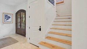 A staircase with wooden steps leading to a landing, a white door with a black handle, and a framed picture on the wall. - 7 BR 8 BA Private Pool Singleton Beach Sleeps 24 Bikes & Beach Gear included (Hilton Head Island)