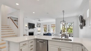 A modern kitchen with a dishwasher, white cabinetry, and a dining area with a view. - 7 BR 8 BA Private Pool Singleton Beach Sleeps 24 Bikes & Beach Gear included (Hilton Head Island)