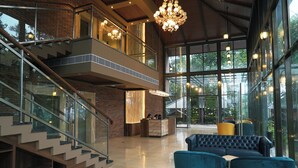 Un vestíbulo amplio con escaleras, zona de estar y grandes ventanales.