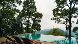 Una piscina con sillones de descanso y vistas a un paisaje montañoso.