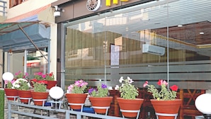A hotel entrance with a glass facade, potted plants, and a sign with the hotel's name. - Hotel Lumbini Airport (Kathmandu)