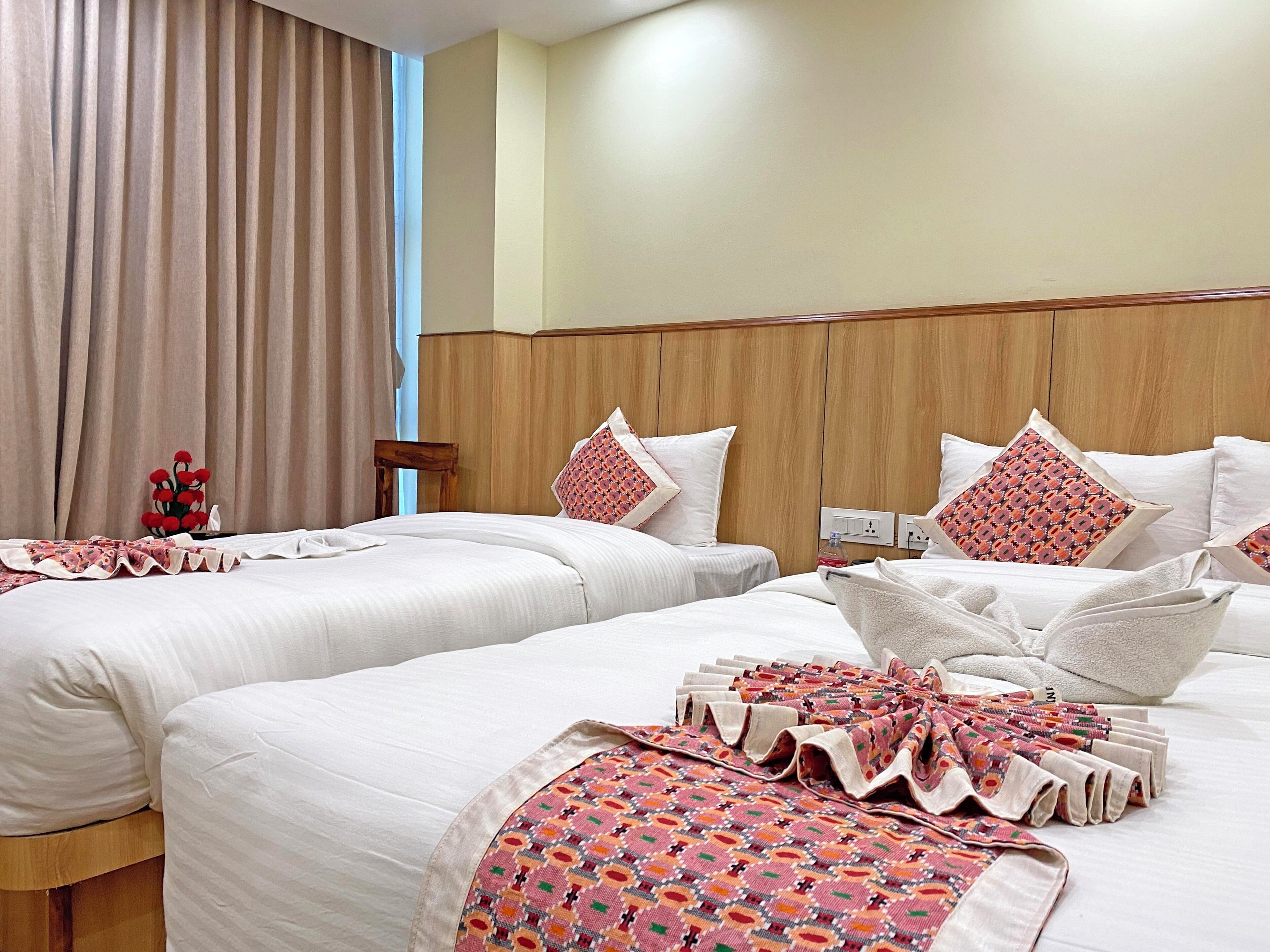A hotel room with two beds, a wooden headboard, and a large window with curtains.
