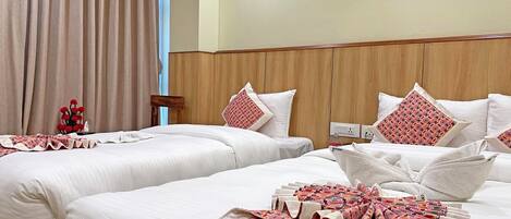A hotel room with two beds, a wooden headboard, and a large window with curtains.