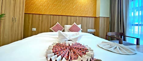 A neatly made bed with a patterned blanket, pillows, and a folded towel.