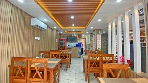 A restaurant interior with wooden furniture, a kitchen area, and a bar. - Hotel Lumbini Airport (Kathmandu)