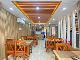 Interior de restaurante con muebles de madera, una zona de cocina y una barra.