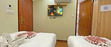 Una habitación de hotel con dos camas, un televisor en la pared y un equipo de aire acondicionado.