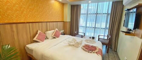 A hotel room with a large bed, a desk, and a TV.