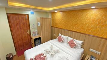 Habitación de hotel con cama, armario, escritorio y teléfono, y pared con diseño decorativo.