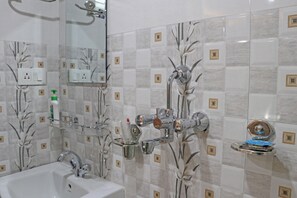 Un baño con lavamanos, espejo y varios grifos.