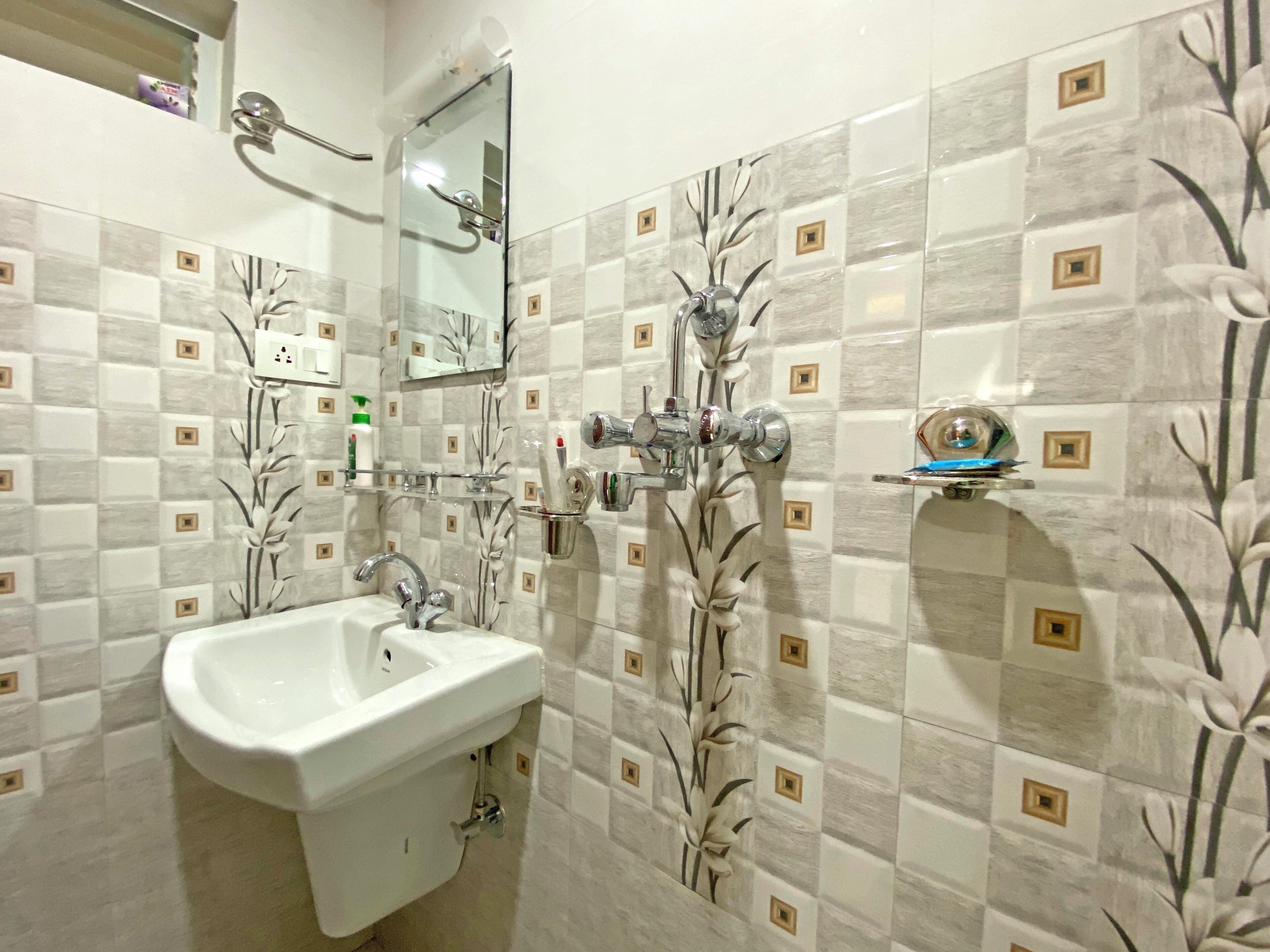 Un baño con lavamanos, espejo y toallero.