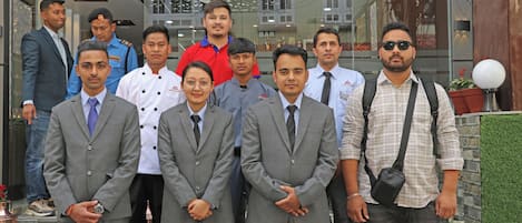 A group of people standing in front of a building with a bar visible through the glass.