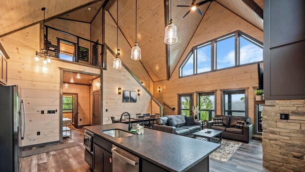 Amplia sala de estar con una isla grande, una cocina con electrodomésticos modernos y una chimenea de piedra.