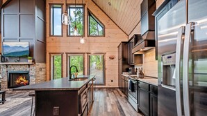Una cocina moderna con una isla grande, electrodomésticos de acero inoxidable y una chimenea de piedra.