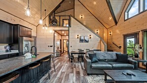 Un interior espacioso con cocina, comedor y sala de estar, que cuenta con pisos de madera y techos altos.
