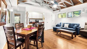 Un vaste espace de vie comprenant une table à manger en bois, un canapé bleu et un ventilateur de plafond.