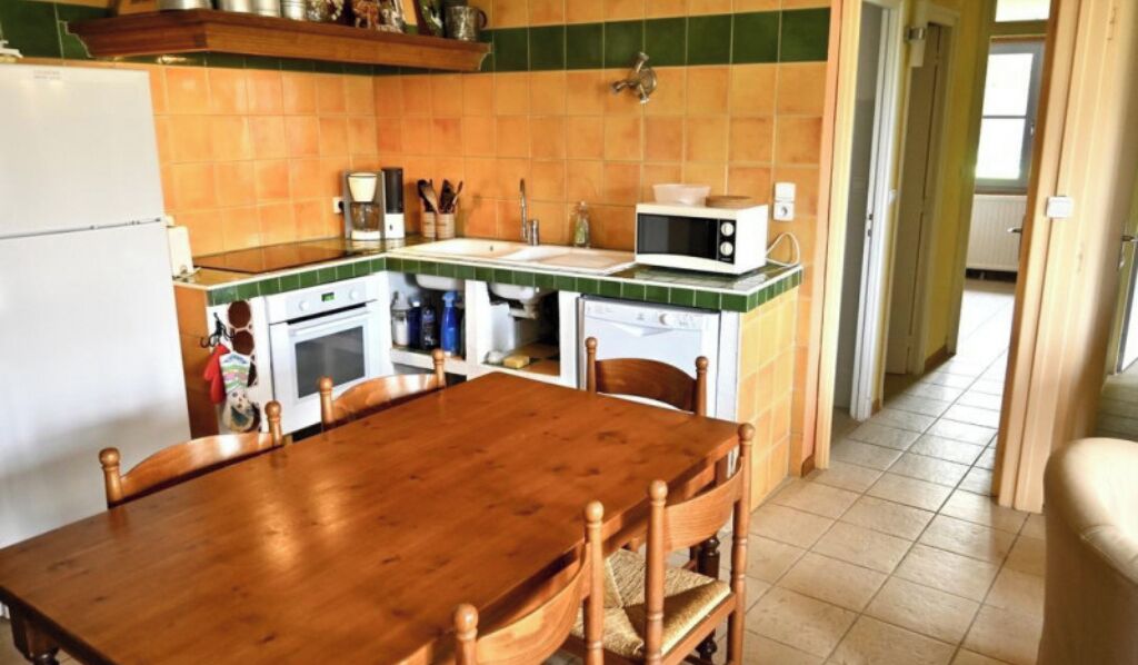 Una cocina con una mesa y sillas de madera, un microondas y un refrigerador.