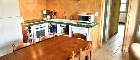 Una cocina con una mesa y sillas de madera, un microondas y un refrigerador.
