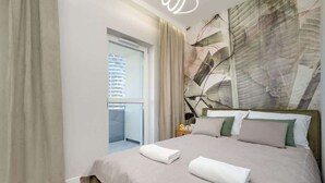 Ein Hotelzimmer mit einem großen Bett, Blick auf ein Gebäude durch das Fenster und einem Gemälde an der Wand.