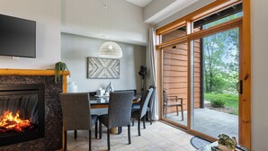 Una sala de estar moderna con chimenea, comedor y grandes puertas corredizas de vidrio que dan a un patio.
