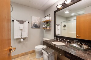 A modern bathroom with a toilet, sink, and mirror. There are towels and a small plant on the wall. - Studio on Green | Chula Vista, Walk to Attractions (Wisconsin Dells)