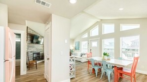 A spacious kitchen with a dining area, wooden floors, and large windows.