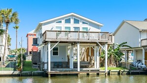 A waterfront house with a covered porch, a small deck, and a boat dock.
