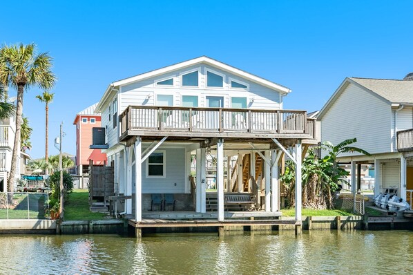 Une maison située au bord de l’eau, dotée d’un porche couvert, d’une petite terrasse et d’un quai pour bateaux.