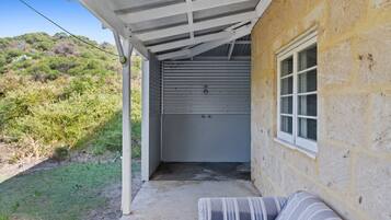 A covered outdoor area with a concrete floor, a white bench, and a garage door.